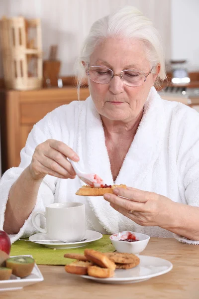 年配の女性が朝食を食べる — ストック写真