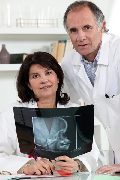 Twee artsen onderzoeken x-ray afbeelding — Stockfoto