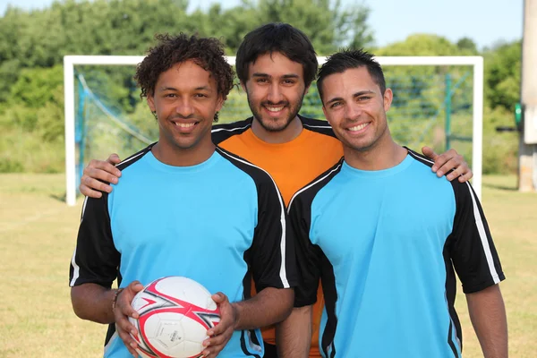 Tre unga fotbollsspelare framför mål — Stockfoto
