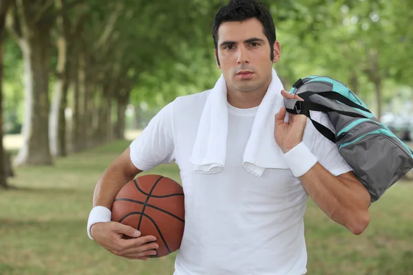 30 anos de idade desportista segurando uma bola de cesta e um saco de esportes — Fotografia de Stock