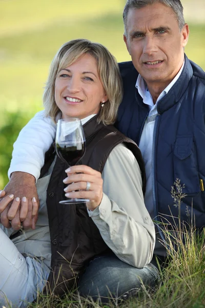 Paar trinkt Wein auf Feld — Stockfoto
