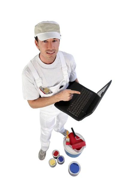 Decorateur met potten met verf en een opengeklapte laptop — Stockfoto