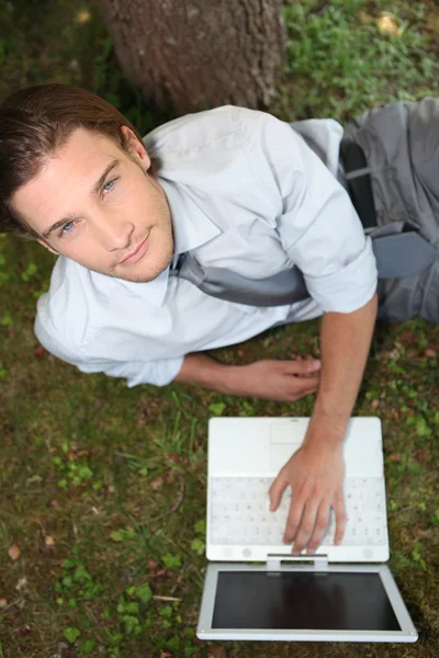 Top view of man laid by tree with laptop — Stock Photo, Image
