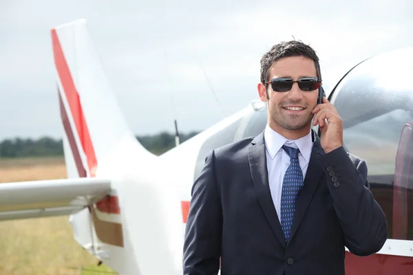 Человек разговаривает по мобильному телефону рядом с частным самолетом — стоковое фото