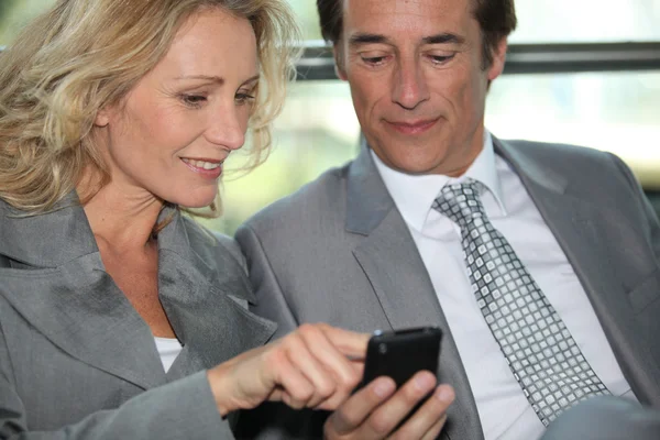 Paar Führungskräfte, die sich etwas auf einem Handy anschauen — Stockfoto