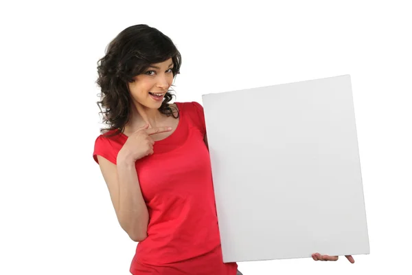 Woman in red pointing at a board left blank for your message — Stock Photo, Image