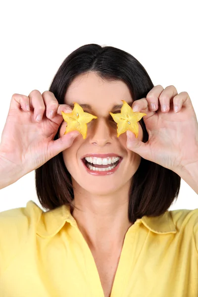 Woman holding slices of starfruit in front of her eyes — Stok fotoğraf