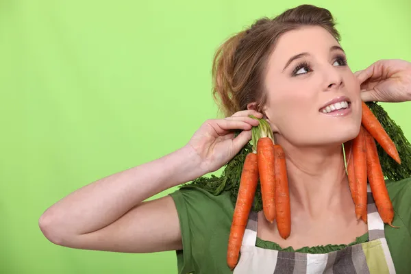 A female cook wearing carrots as earrings — Stock Photo, Image