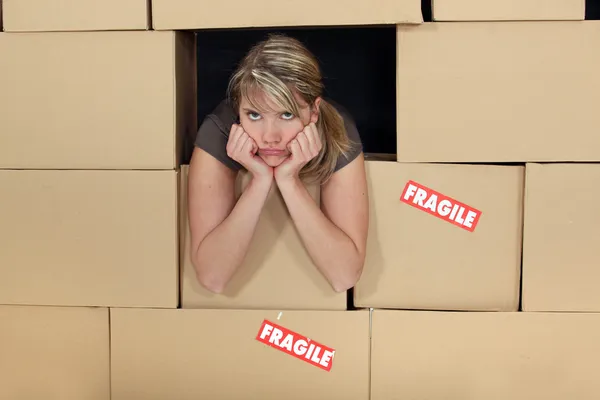 Uttråkad kvinna omgiven av lådor — Stockfoto