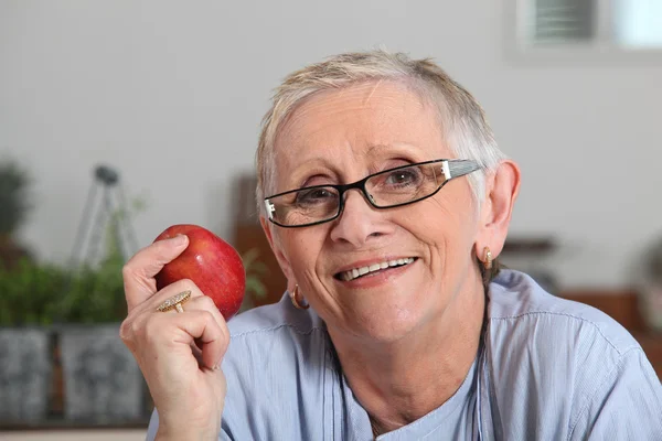 Senior vrouw met appel in de hand — Stockfoto
