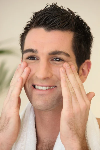 Retrato de um homem sorridente aplicando creme — Fotografia de Stock