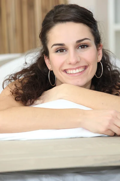 Vrouw liggend op het bed glimlachen — Stockfoto
