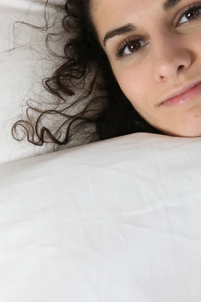 Ung kvinna gömmer sig under täcket — Stockfoto