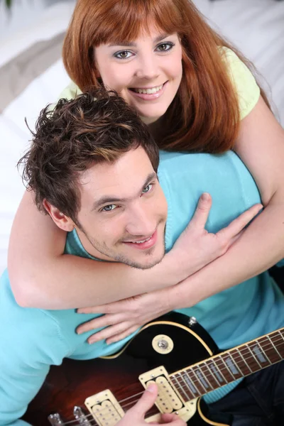 Mladý pár doma s kytarou — Stock fotografie