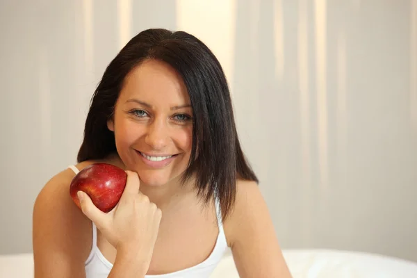 Mujer con una manzana roja en la cama — Foto de Stock