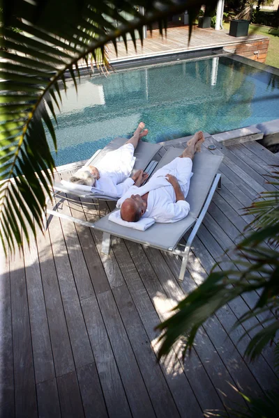 stock image Elderly couple on sunloungers by a pool