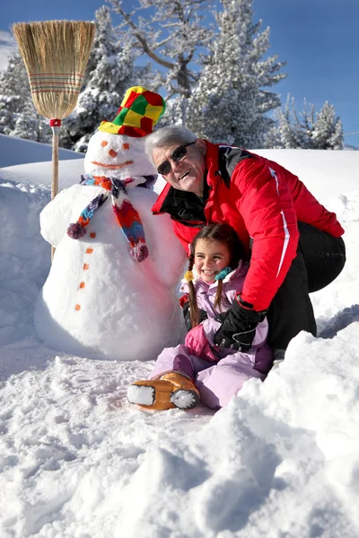 Man playing with his granddaughter in the snow — Stock Photo, Image