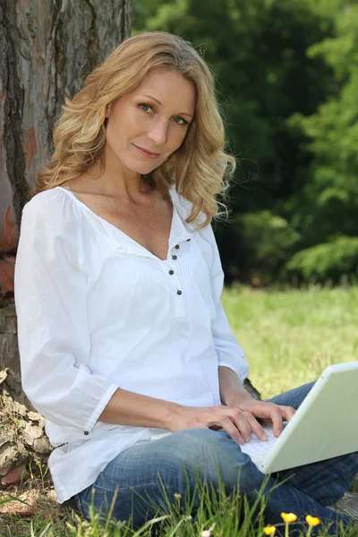 Kvinna på laptop under träd — Stockfoto