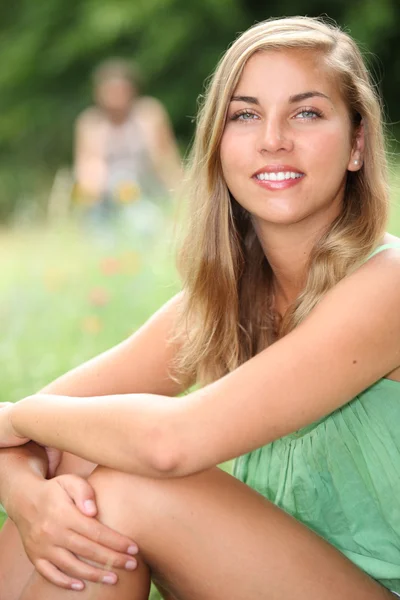Junge Frau sitzt im Sommer auf einer Wiese — Stockfoto