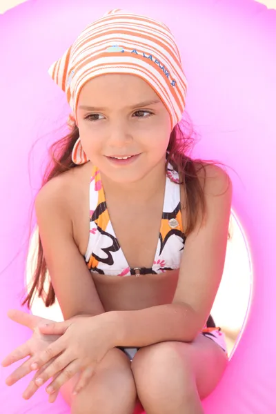 Ung tjej i bikini som sitter i en uppblåsbar beach ring — Stockfoto