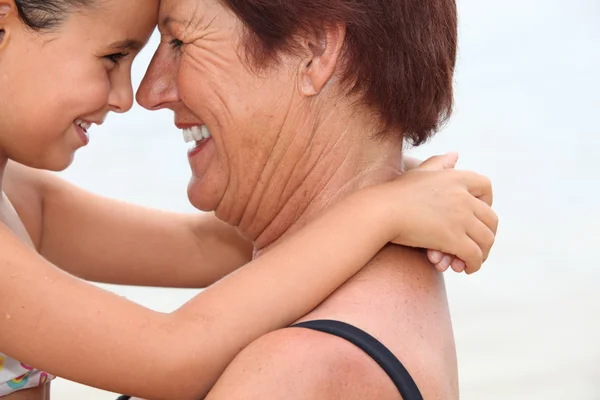 Mormor näsa till näsa med dotterdottern på stranden — Stockfoto