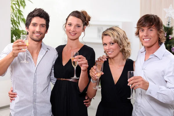 Four toasting in front of a Christmas tree — Stock Photo, Image