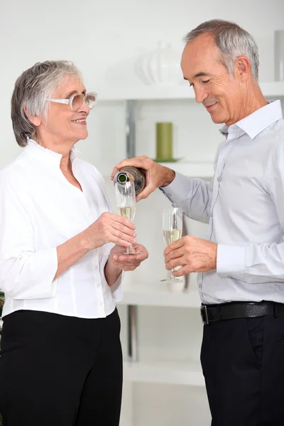 Зрелый мужчина наливает жене игристое вино — стоковое фото