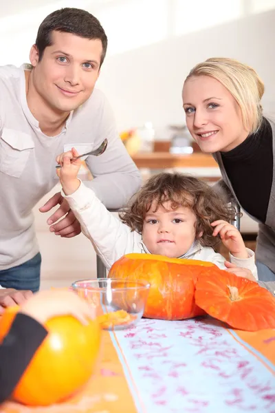 Ein kleines Kind isst einen Kürbis und seine Eltern — Stockfoto