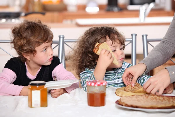 Dos niños en la mesa de la cocina desayunando — Foto de Stock