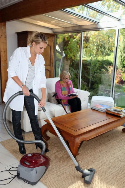 Tjej vacuuming för en äldre kvinna Royaltyfria Stockfoton