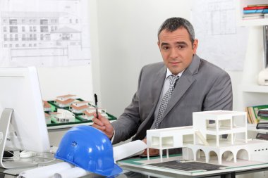 Architect in office surrounded by plans clipart