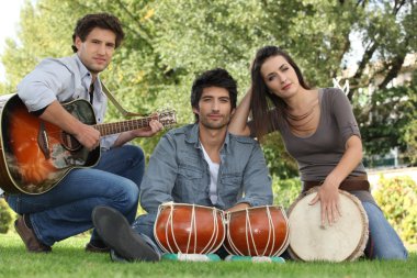 Three musicians in a park clipart