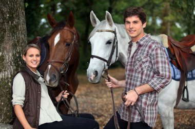Young couple and horses in forest clipart