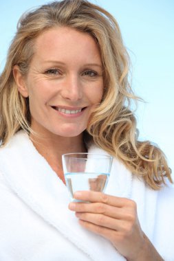 Woman drinking a glass of water in a bathrobe clipart