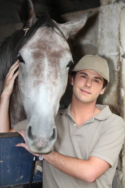 Young man and horse at a stable clipart