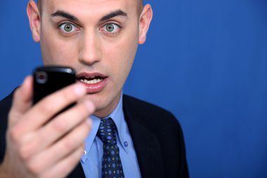 Shocked man looking at mobile telephone clipart