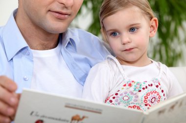 Father reading a story to his daughter clipart