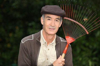 65 years old man wearing brown clothes and holding a rake clipart