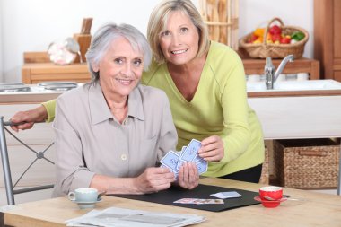 Two mature women playing cards. clipart