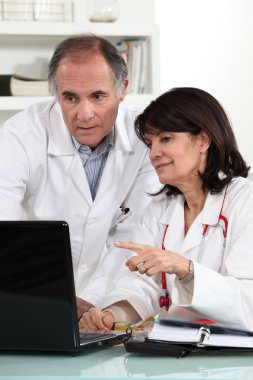 Doctors looking at a computer and sharing their opinions clipart