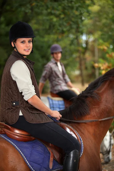 Чоловік навчає блондинку підлітка кататися на конях — стокове фото