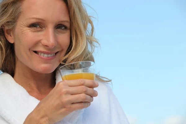 Donna bionda all'aperto che beve succo d'arancia — Foto Stock