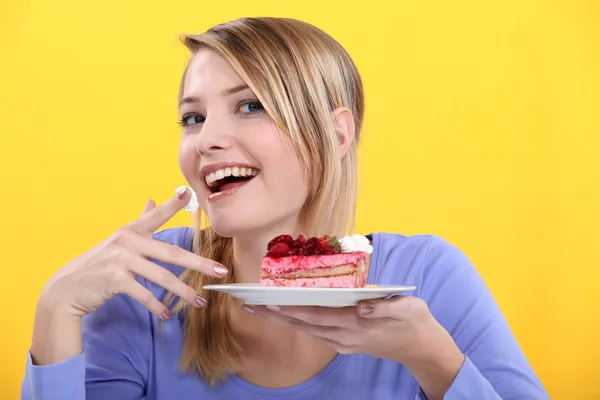 Wanita muda makan sepotong kue — Stok Foto