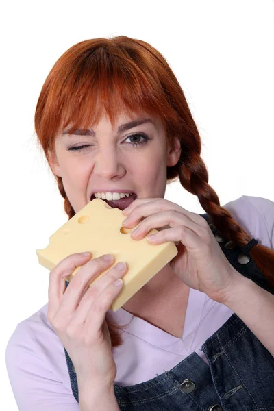 Woman biting into block of cheese — Stock Photo, Image