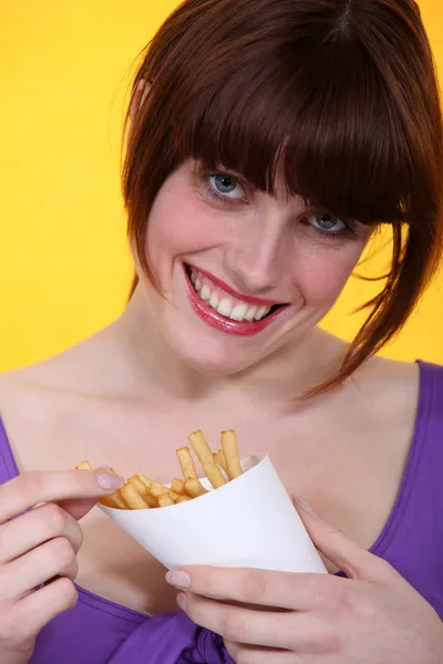 Brunette genieten van Franse frietjes. — Stockfoto
