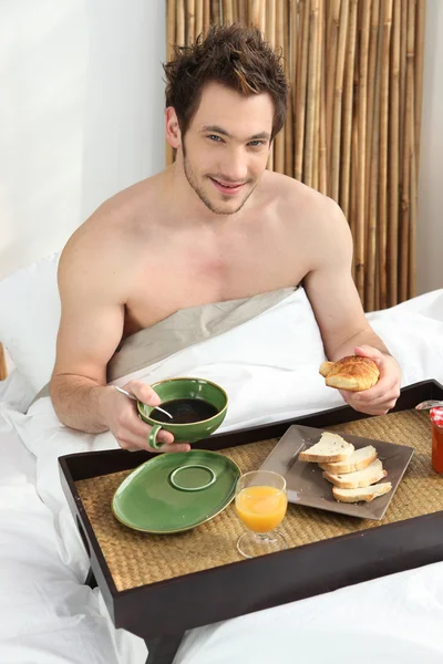 Jovem tomando café da manhã na cama — Fotografia de Stock