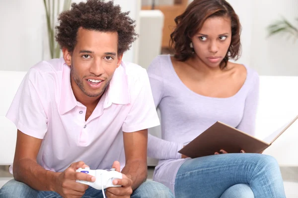 Hombre jugando videojuegos y mujer leyendo — Foto de Stock