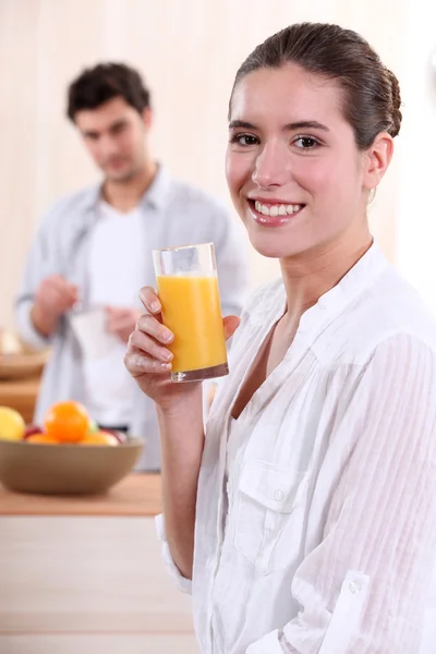 Vrouw drinken van een glas sinaasappelsap voor ontbijt — Stockfoto