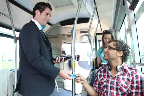 En ung controller kontrollera passagerare i en buss. — Stockfoto