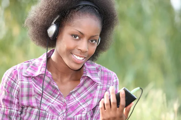Beautiful black woman listening music in the park — Stock Photo, Image